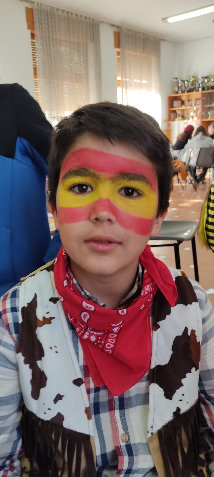 Niño con maquillaje en cara de bandera de España.