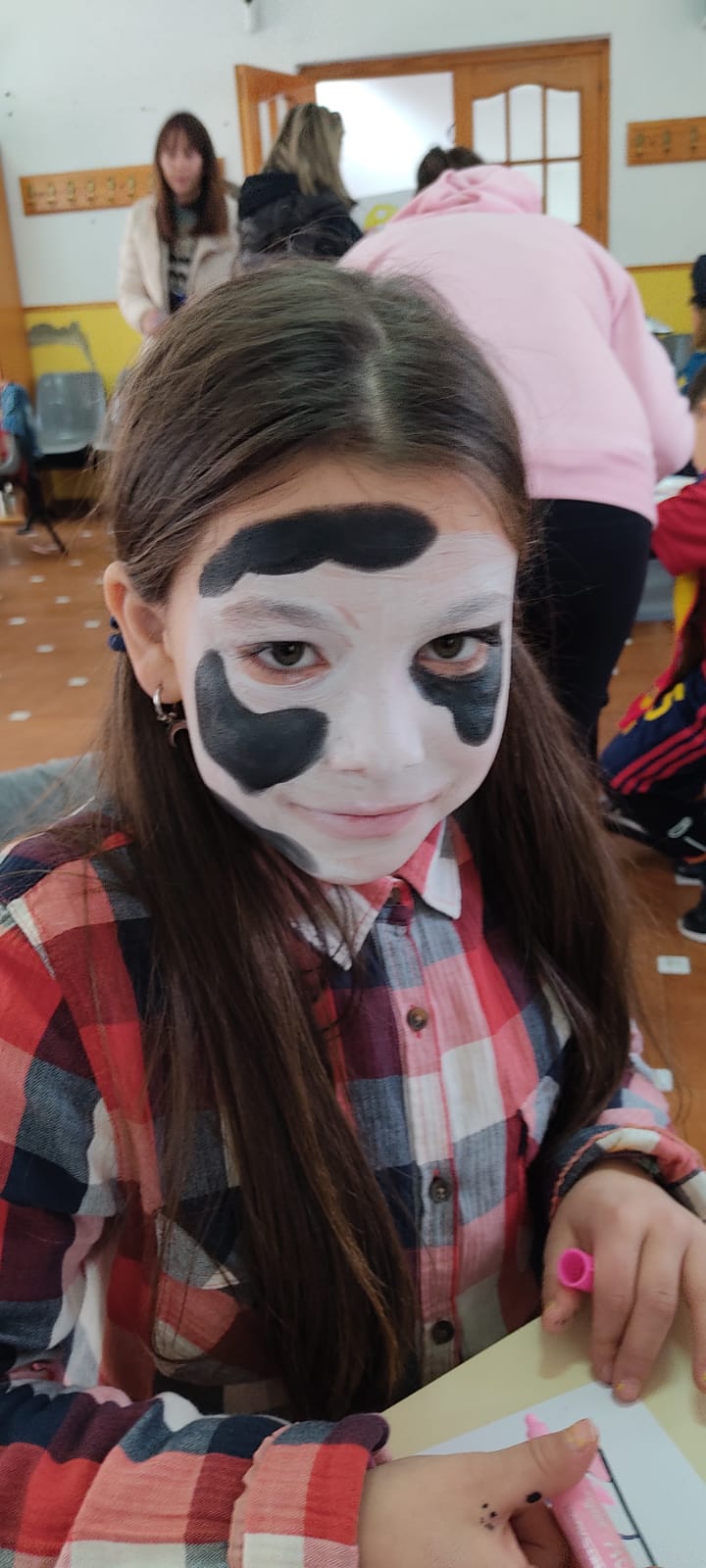 Maquillaje infantil de carnaval con piel de vaca en la cara, en niña vestida de baquera.